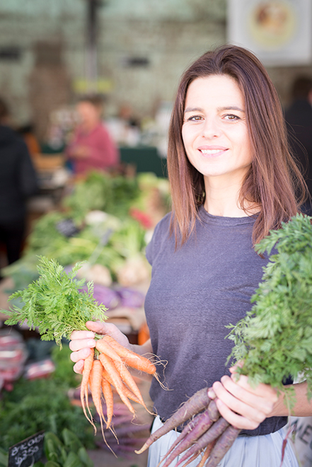 Woman holding two bunches of carrots at a market